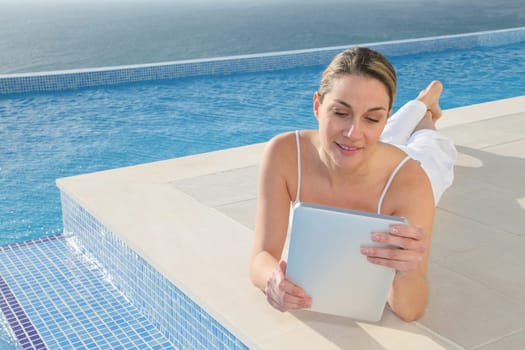 Woman using electronic tablet by swimming pool