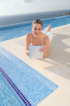 Woman using electronic tablet by swimming pool