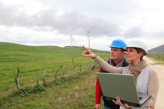 Engineers working by wind turbines field