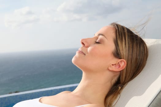 Woman relaxing in deckchair by swimming-pool