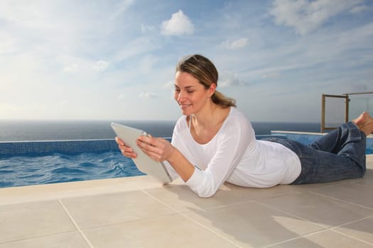 Woman using electronic tablet by swimming pool