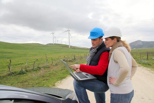 Engineers working by wind turbines field