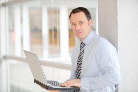 Businessman standing in hall with laptop computer