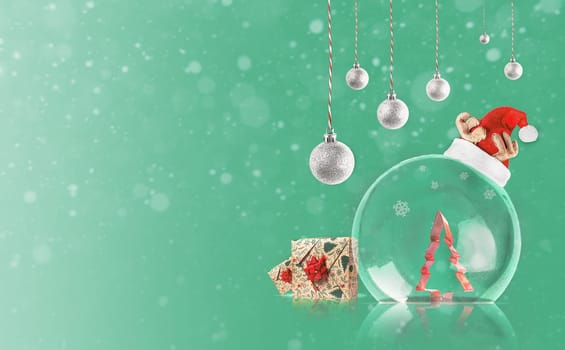 Transparent Christmas ball with Christmas tree inside. Silver decoration on green background with copy space. Merry Christmas.
