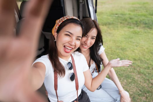 Car road trip traveling couple tourists enjoying mountain view relaxing on car. Happy Asian woman, women girlfriends smiling on car.