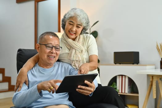 Senior couple browsing internet or watching video on digital tablet. Retirement lifestyle concept.