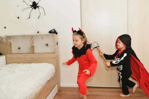 Children in skeleton and witch costume laughing at home halloween