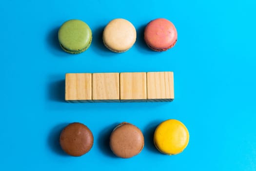 Colorful cake macaron or macaroon on a blue background. Flat lay, top view, copy space