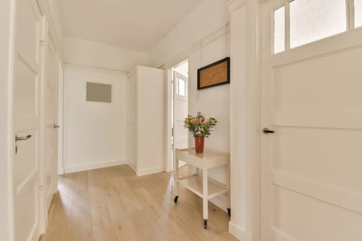 a hallway with white walls and wood flooring in an empty house, showing the entrance way to another room