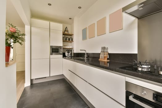 a modern kitchen with black counter tops and white cabinets in the photo is taken from the front door to the left