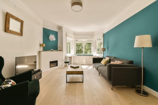 a living room with teal blue walls and white trim on the walls, hardwood flooring is light wood