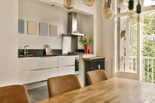 a kitchen and dining area in a modern home with white walls, wood flooring and large windows looking out onto the street