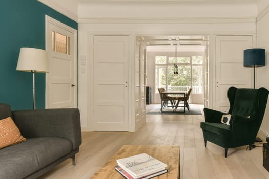 a living room with blue walls and white trim on the walls, wood flooring and green chair in the middle