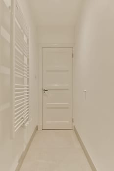 a long hallway with white walls and flooring on both sides, there is an open door in the middle