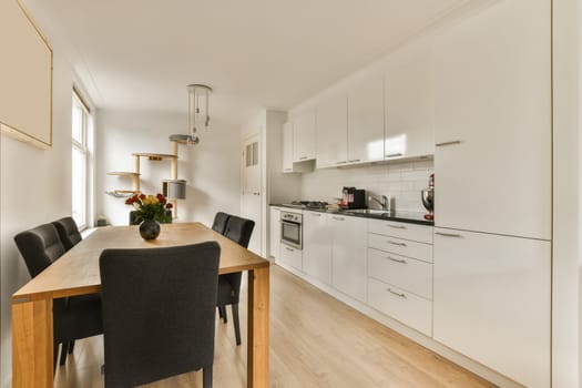 a kitchen and dining area in a modern apartment with white walls, hardwood flooring and light wood table top