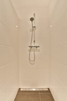 a shower with white tiles on the walls and brown wood flooring in a modern style bathroom area that is clean and ready for