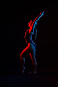 Sportive exercises, standing and stretching the hands. Beautiful muscular woman in indoors studio.