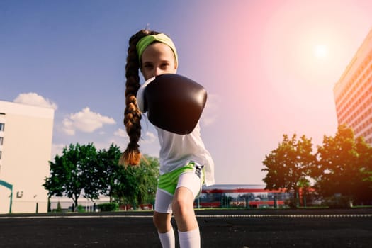 Female child boxer in gloves, feminism concept. Back to school, physical training.
