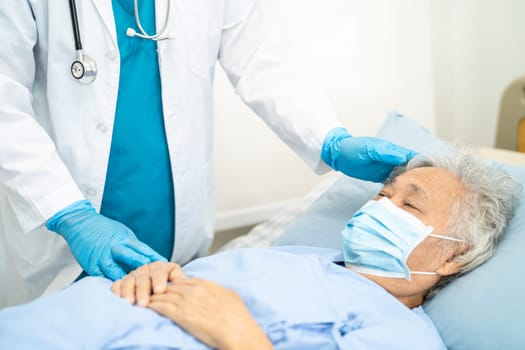 Doctor checking Asian senior woman patient wearing a face mask in hospital.