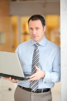 Businessman standing in hall with laptop computer