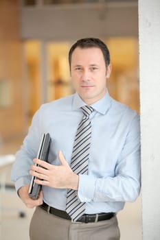 Businessman standing in hall with laptop computer