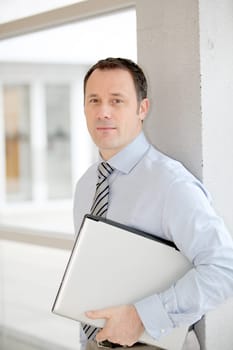 Businessman standing in hall with laptop computer