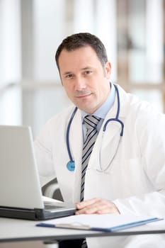 Doctor sitting at his desk with laptop computer