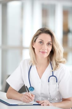 Beautiful nurse in hospital writing on notepad