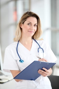 Beautiful nurse in hospital writing on notepad