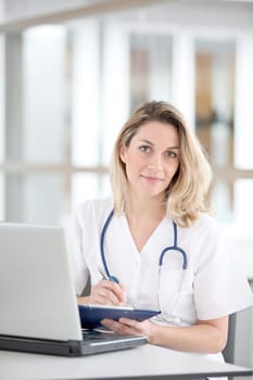 Beautiful nurse in hospital writing on notepad