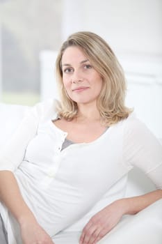 Portrait of beautiful blond woman sitting on sofa