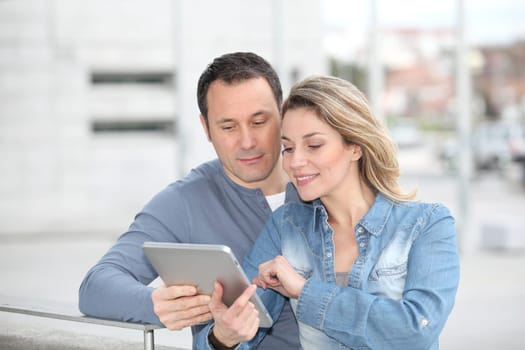 Couple using electronic tab in the street