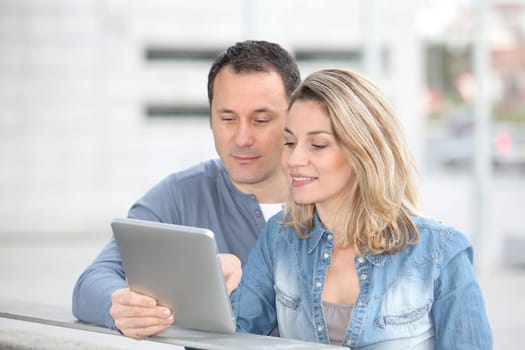 Couple using electronic tab in the street