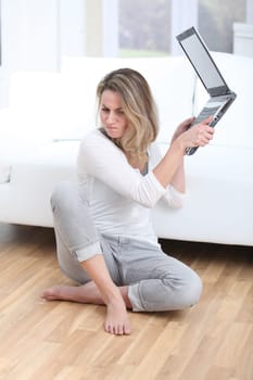 Blond woman throwing laptop computer on the floor