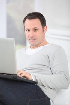 Man sitting in couch using laptop computer