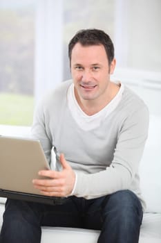 Man sitting in couch using laptop computer