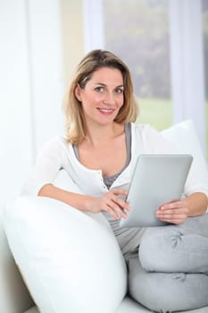 Woman using electronic tab sitting in couch