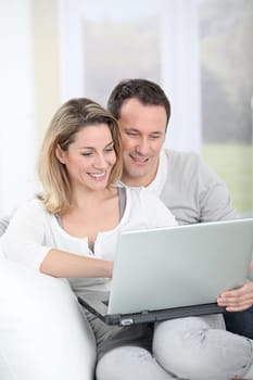 Couple sitting in sofa with laptop computer
