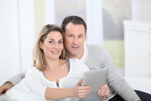 Couple sitting in sofa with electronic tab