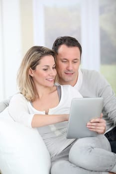 Couple sitting in sofa with electronic tab