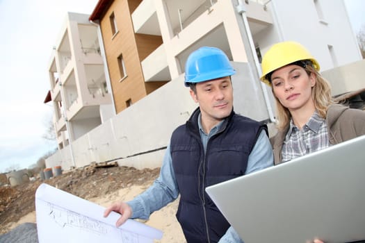 Architect and engineer looking at plan on construction site
