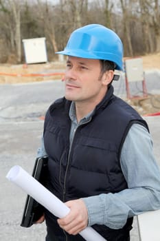 Site supervisor with security helmet standing on construction site