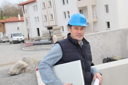 Site supervisor with security helmet standing on construction site
