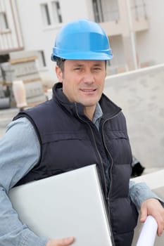 Site supervisor with security helmet standing on construction site