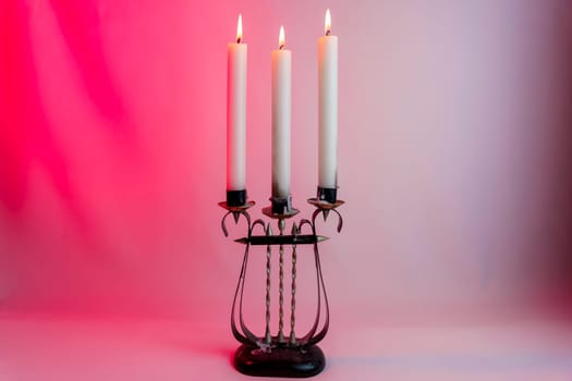 Elegant antique candelabrum with three lit candles, casting a warm glow on a red and purple gradient background. Perfect for romantic, gothic, and vintage-themed designs