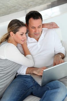 Couple relaxing in sofa with laptop computer