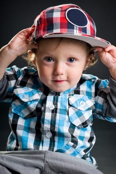 Casual cool young kid with cap against gray background