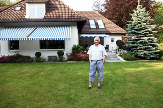 Friendly senior in front of his house in casual look