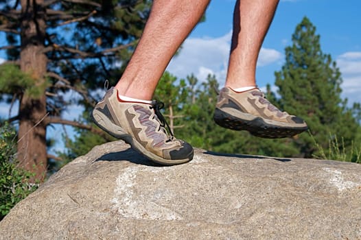 Trail runner climbing a steep rock in his path