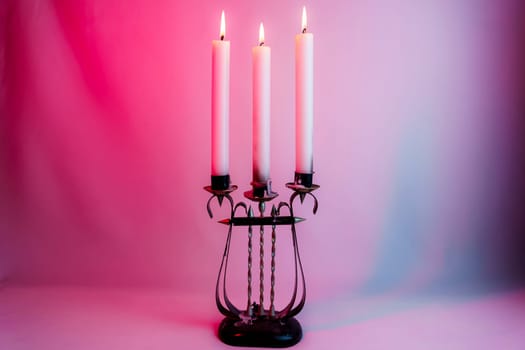 Elegant antique candelabrum with three lit candles, casting a warm glow on a red and purple gradient background. Perfect for romantic, gothic, and vintage-themed designs